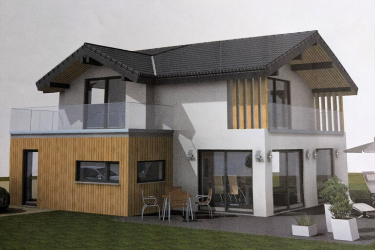 Ein modernes zweistöckiges Haus mit großen Fenstern, einem Balkon, einem dunklen Ziegeldach und Holzverkleidungen. Die Terrasse ist mit Gartenmöbeln ausgestattet und das Haus ist von grünem Rasen umgeben. Die Gärtner im Allgäu