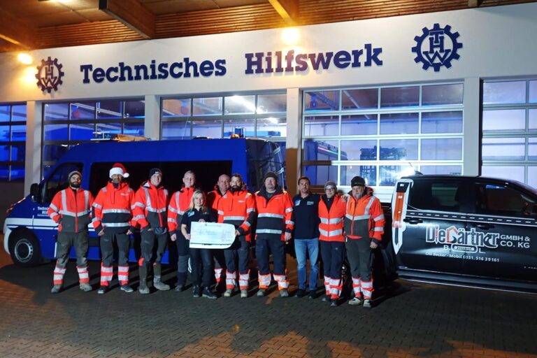 Eine Gruppe von Personen in orangefarbenen Sicherheitswesten steht vor einem Gebäude mit der Aufschrift Technisches Hilfswerk neben blauen und schwarzen Fahrzeugen und hält nachts eine große feierliche Kontrolle ab. Die Gärtner im Allgäu